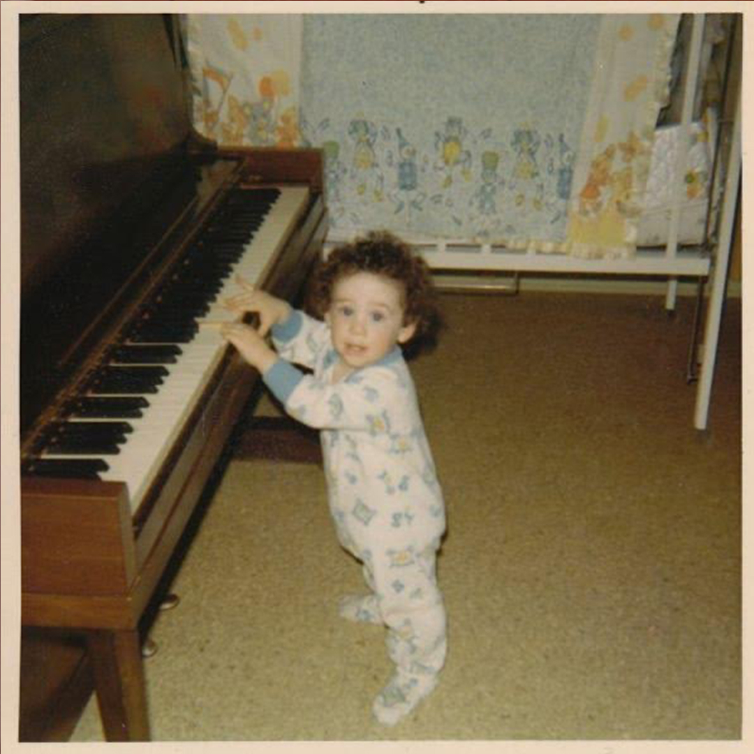 Rob as a toddler reaching for the piano keys