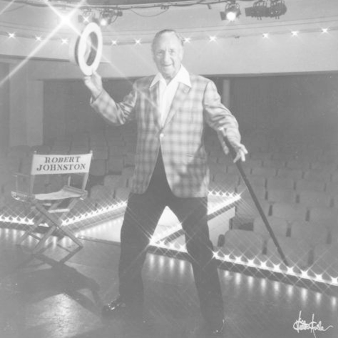 Robert Johnston on stage beside a director's chair bearing his name